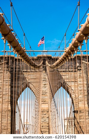The old glory flying over the arches of Brooklyn Bridge in New York City