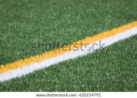 Diagonal parallel yellow and white boundary stripe painted on artificial green grass turf athletic field 