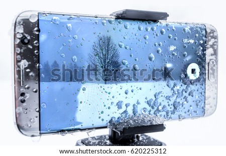 Cell phone covered in ice and water being used to shoot video in a cold snow storm.