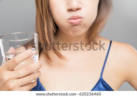Woman rinsing and gargling while using mouthwash from a glass, During daily oral hygiene routine, Portrait with bare shoulders, Dental Health Concepts Royalty-Free Stock Photo #620236460