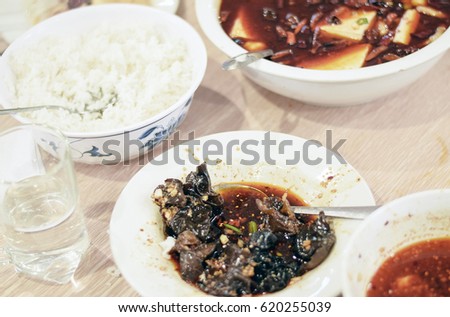 People eating Szechuan Chinese food at a meal around a restaurant table