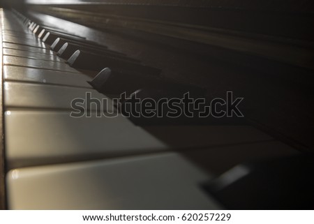 Close up vintage background of wood classical acoustic grand piano keyboard with sepia toned white and black keys. Creative full screen composed macro photography with tilt effect by tilt-shift lens.