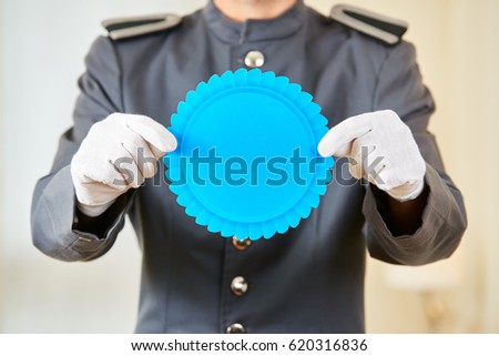 Hands of hotel concierge holding a blank blue badge