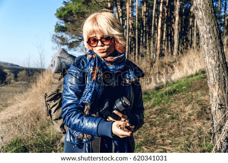 Girl with a backpack and a camera walks the hill through the forest Active lifestyle, morning with coffee in the open air Inspiration Tired to go, we have already come ?, a break on vacation