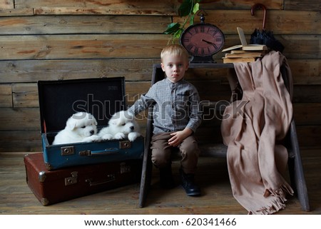 Puppies Husky and the child in a room with wooden walls, with an old clock on the wall. Husky dog symbol of the year 2018