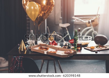 Messy table with pizza in box and beverages at morning after party Royalty-Free Stock Photo #620398148