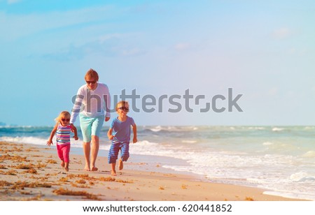 father with little son and daughter run at beach