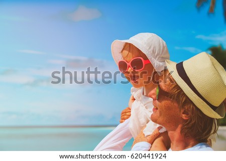 father and little daughter play on beach