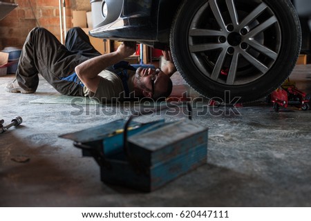 mechanic fixing a car at home	 Royalty-Free Stock Photo #620447111