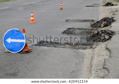  Road repairs. Plastic orange cone on the asphalt road. Detour sign on the street, roadworks. Restricted local government budgets are reflected in potholes and damaged roads.