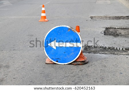  Road repairs. Plastic orange cone on the asphalt road. Detour sign on the street, roadworks. Restricted local government budgets are reflected in potholes and damaged roads.