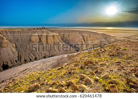 Beautiful Israeli desert landscape, with sunrise over the Qumran Caves archaeological park, where the Dead Sea scrolls have been discovered, and dry Judean Desert wadi (canyon) leading to the Dead Sea Royalty-Free Stock Photo #620461478