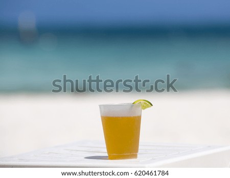 Cold beer on the beach. Turquoise water in the background. 
