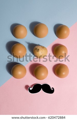 Eggshells lined up with a potato hidden in the batch
blue and pink background with black shadow