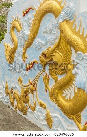 sculpture of gold dragon on the wall in temple