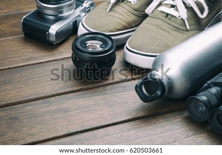 Camera, lens, binocular, canvas shoes, sports bottle on the retro wooden table 