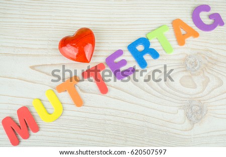 The German word for mothers day in colorful letters with a red heart, text diagonal and copy space
