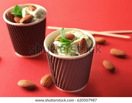 Tasty ice cream with almonds on color background