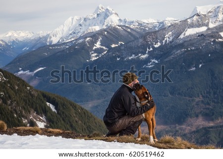 Man embraces the dog that's licking his face after a hike to the summit. Picture taken on top of Elk Mountain, Chilliwack, BC, Canada.