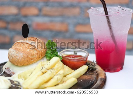 Burger and cheese with french fries served with sweet red syrup and soda drink