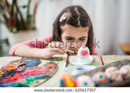 Little girl coloring easter eggs in her home
