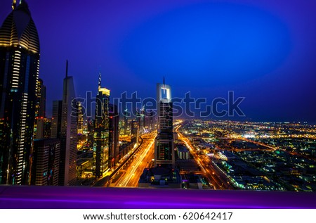Dubai by night with blurry lights. Picture took from the top of the hotels's terrasse with highlighted barrier on the foreground. Sheikh Zayed Road by night. Dubai skyscrapers.
