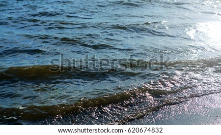 Sea waves on the beach dissolve in the rays of the sun. The marine nature of water. The idyllic scene of tranquility.