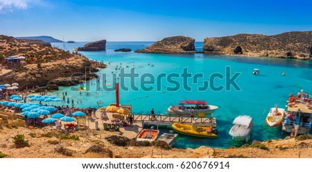 Comino, Malta - Tourists crowd at Blue Lagoon to enjoy the clear turquoise water on a sunny summer day with clear blue sky and boats on Comino island, Malta. Royalty-Free Stock Photo #620676914