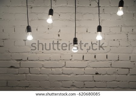 Retro light bulbs hang in interior with white brick wall background. light bulbs hanging on brick wall backdrop