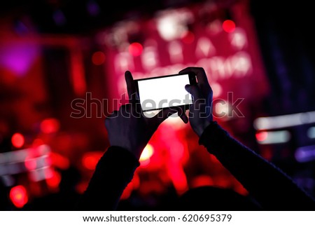 Hands with a smartphone records live music festival, live concert, show on stage