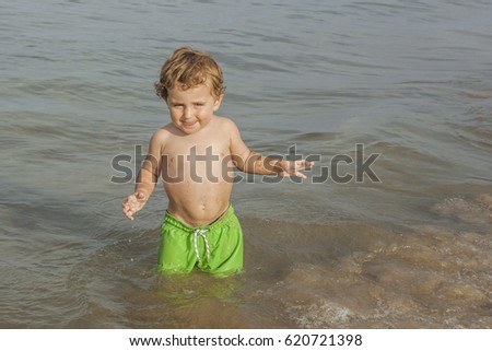 Boy wearing swimsuit playing in the seashore of the beach. Summertime. 