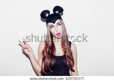 Funny girl show peace sigh represents small cat or mouse. Woman with bright makeup hairstyle and night dress mouse ears having fun. On white background not isolated