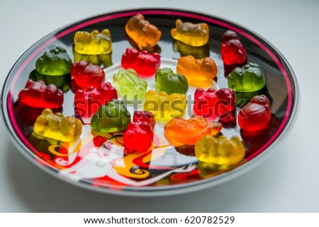 many different gummycandies on white black plate. sweet pieces of colored fruits gummy vitamins as part of a delicious dessert. Bright tasty colorful kids eating healthy