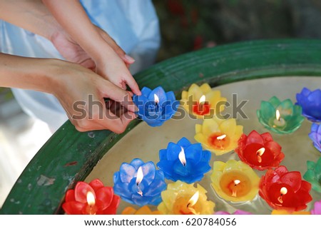 Hands holding lotus candle on the water, Thailand