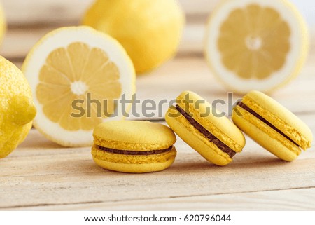 Yellow french macarons with lemons on the wooden board, soft focus background