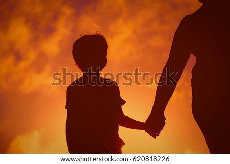 Silhouette of family holding hands at sunset sky