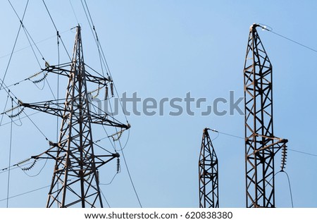 Three power transmission towers. High voltage. Blue background.
