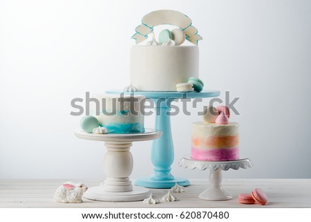 Delicious cakes on various cake stands. Bunny, macaroni sweets and meringues on the wooden surface, place to insert your text. Gourmet dessert.