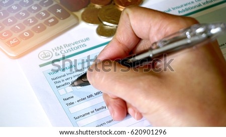 Photo of filling in a HM customs form a personal details for UK self assessment tax and benefits right. Royalty-Free Stock Photo #620901296