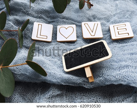 Rustic love. Love wooden letters. Empty chalkboard with eucalyptus on blue background. Rustic background.