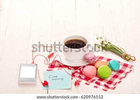 Coffee, macaroons and cream with a good morning card on a white table