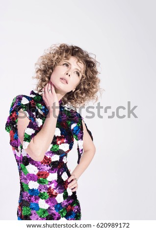 Young beautiful woman chooses something or thinks about something. Curly hair and bright dress. White background with free space