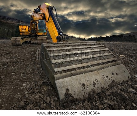 wide angle, threatening view of an excavator with a stormy sky brewing in the distance Royalty-Free Stock Photo #62100304