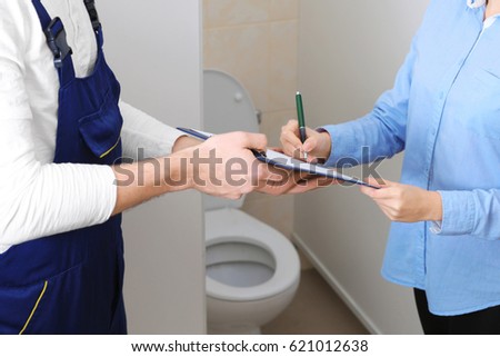 Female customer signing contract with plumber indoors