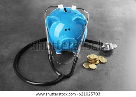 Piggy bank with stethoscope and coins on table