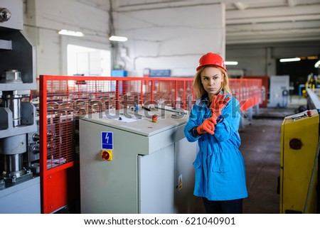 beautiful woman in red safety helmet work as industrial worker at metal sheet profiling mechine at manufacturing factory