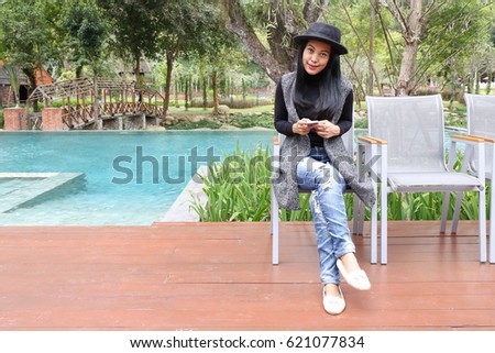 Charming beautiful tan skin Asian woman use phone at swimming pool side. 