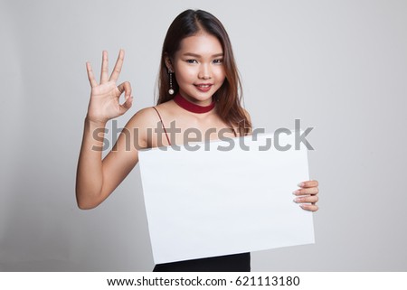 Young Asian woman show OK with white blank sign on gray background