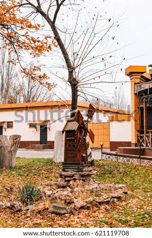 A wooden mill in the park. Element of landscape design of the park. Golden Autumn, yellow leaves on the trees.