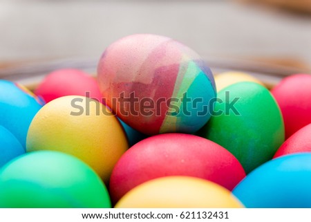 Painted eggs lie on a plate in a stack for Easter